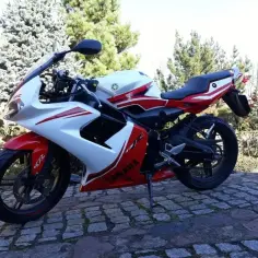 Sportowy motocykl Yamaha TZR 50 w czerwono-białych barwach, gotowy do jazdy z maksymalną prędkością.