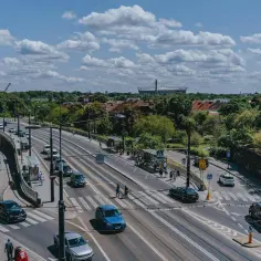 Na skrzyżowaniu z tramwajami, samochody zatrzymują się przed linią warunkowego zatrzymania. W tle widać stadion.