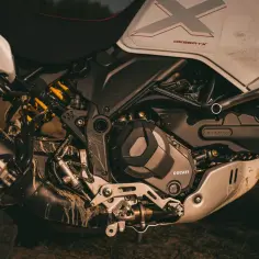 Zbliżenie na silnik i zawieszenie motocykla Ducati DesertX, ubrudzonego błotem po off-roadowej przygodzie.