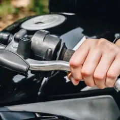 Dłoń na kierownicy motocykla, zegarek na nadgarstku. Zastanawiasz się, rpm co to? To obroty silnika.