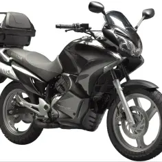 Czarny motocykl Honda Dominator z kufrem na bagaż, gotowy na dalekie podróże.