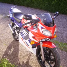 Sportowy motocykl Honda NSR 125 w czerwono-biało-niebieskich barwach, gotowy do jazdy. Dane techniczne tego modelu są imponujące.