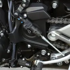 Mechanizm quickshifter przy skrzyni biegów motocykla. To urządzenie pozwala na błyskawiczną zmianę biegów bez sprzęgła.