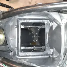 Wnętrze obudowy filtra powietrza motocykla, widoczna odma silnika.