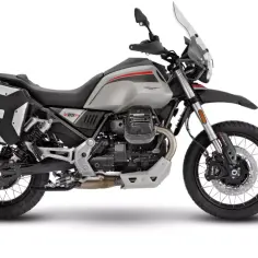 Srebrny motocykl Moto Guzzi V85 TT z czarnymi kuframi, gotowy na przygodę.