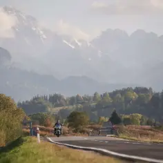 Motocyklista przemierza malowniczą drogę wśród jesiennych krajobrazów. Idealne gotowe trasy motocyklowe czekają na odkrycie.