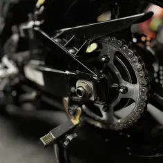 Zbliżenie na tylne koło motocykla z widocznym łańcuchem i zębatką, gotowe do czyszczenia łańcucha motocyklowego.