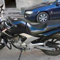 Czarny motocykl Yamaha YBR 250 z chromowanymi elementami, zaparkowany obok niebieskiego samochodu.