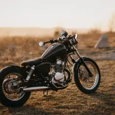 Czarny motocykl Honda Rebel 125 na tle zachodzącego słońca.