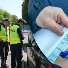 Policjanci wypisują mandat za wymuszenie pierwszeństwa. Kierowca otrzymał karę finansową.