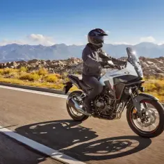 Motocyklista na motocyklu Honda CB500X przemierza malowniczą drogę wśród gór.