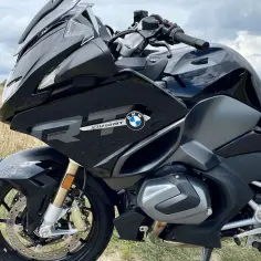 Czarny motocykl BMW R 1250 RT Triple Black na tle pola i chmur.
