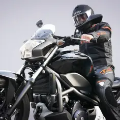 Motocyklista w kasku i kombinezonie siedzi na czarnym motocyklu. Idealny do nauki kategorii prawa jazdy na motor.