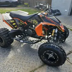 Pomarańczowo-czarny quad Yamaha Blaster 200 z naklejkami "Ready to Race" i amortyzatorami Öhlins, gotowy na przygodę.