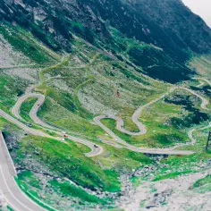 Kręta droga Transalpina w Rumunii, wijąca się po zielonych zboczach gór.
