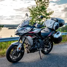 Kawasaki Versys 650 dane techniczne: turystyczny motocykl gotowy na przygodę, z kuframi i bagażem, na tle malowniczego krajobrazu.