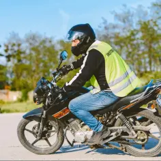 Mężczyzna w kamizelce odblaskowej uczy się jeździć motocyklem. Od ilu lat można zdobyć prawo jazdy a1?