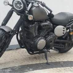 Stojący na chodniku, ciemnoszary motocykl Yamaha chopper z okrągłym reflektorem i czarnym siedzeniem.