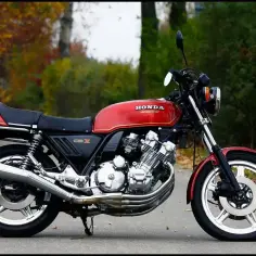 Klasyczny, czerwony motocykl Honda CBX 1000 z lat 80. stoi na tle jesiennego krajobrazu.