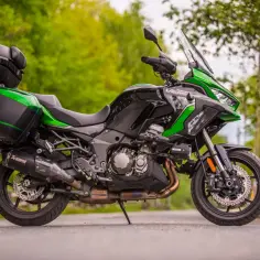 Zielono-czarny motocykl Kawasaki Versys 1000 z kuframi, zaparkowany na drodze.