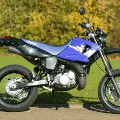 Niebieski motocykl Yamaha DT 125 na trawie. Poznaj yamaha dt 125 dane techniczne i możliwości tego zwinnego sprzętu.