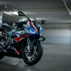 Sportowy motocykl BMW XR w barwach M, z niebieskimi światłami, gotowy do jazdy po torze.
