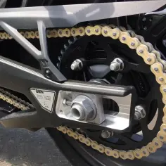 Złoty łańcuch motocyklowy na czarnej zębatce. Dowiedz się, jak liczyć ogniwa w łańcuchu motocyklowym, by zapewnić jego prawidłowe działanie.