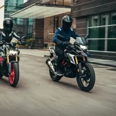 Dwóch motocyklistów na motocyklach BMW G 310 R pędzi ulicą.