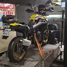 Żółto-czarny motocykl na hamowni, gotowy do testów. To skrót do świata, gdzie konie mechaniczne pokazują swoją moc.
