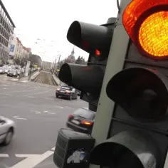 Pomarańczowe światło sygnalizatora, ruch uliczny, tramwaj i budynki. Gdzie są kamery rejestrujące przejazd na czerwonym świetle?