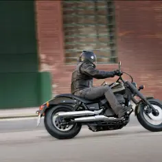 Motocyklista na Honda Shadow 750, z uwzględnieniem danych technicznych, przemierza miejską ulicę.