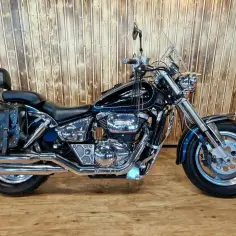 Błyszczący, granatowy Suzuki Marauder z sakwami i chromowanymi elementami, gotowy na podróż.