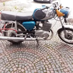 Klasyczny mz ts 250 na bruku, obok przechadza się kot.
