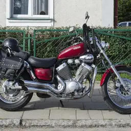 Czerwony motocykl Yamaha Virago 535 z sakwami i kaskiem. Dane techniczne tego klasyka są imponujące.