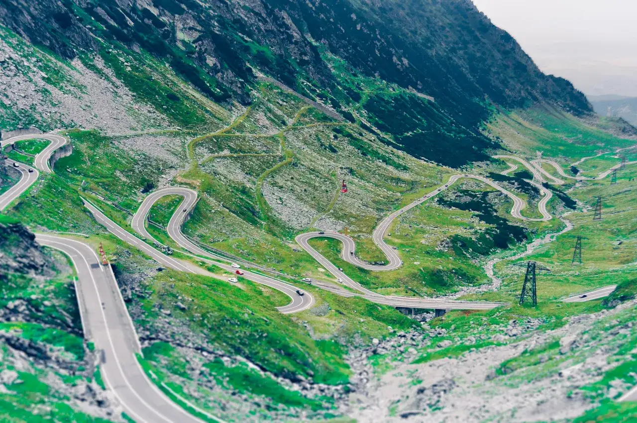 Kręta droga Transalpina w Rumunii, wijąca się po zielonych zboczach gór.