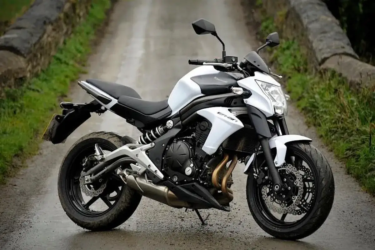 Biały motocykl Kawasaki ER6N na mokrej, kamienistej drodze.