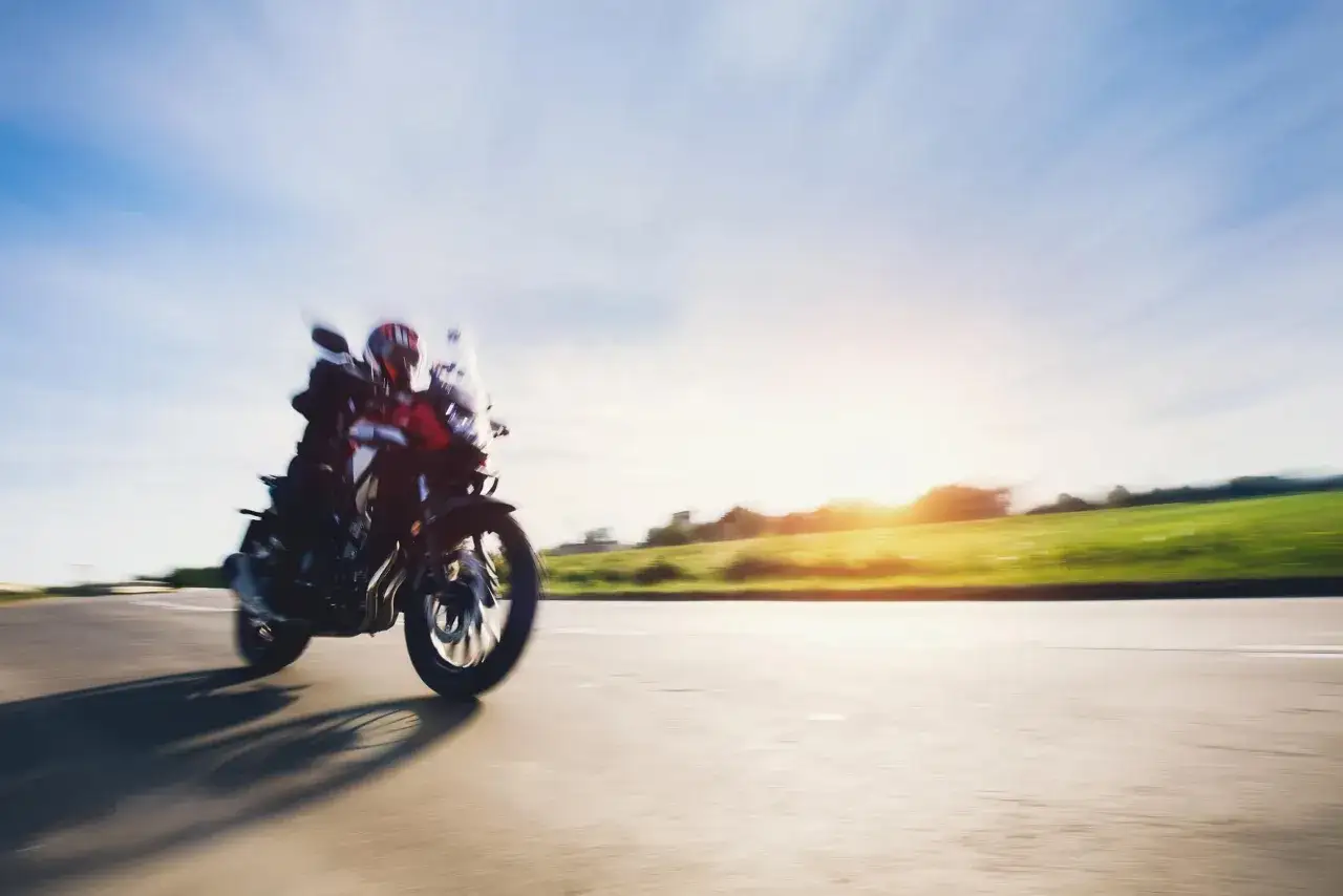 Motocyklista w kasku pędzi po pustej drodze, ciesząc się wolnością i pięknymi widokami. Idealne gotowe trasy motocyklowe czekają na odkrycie.