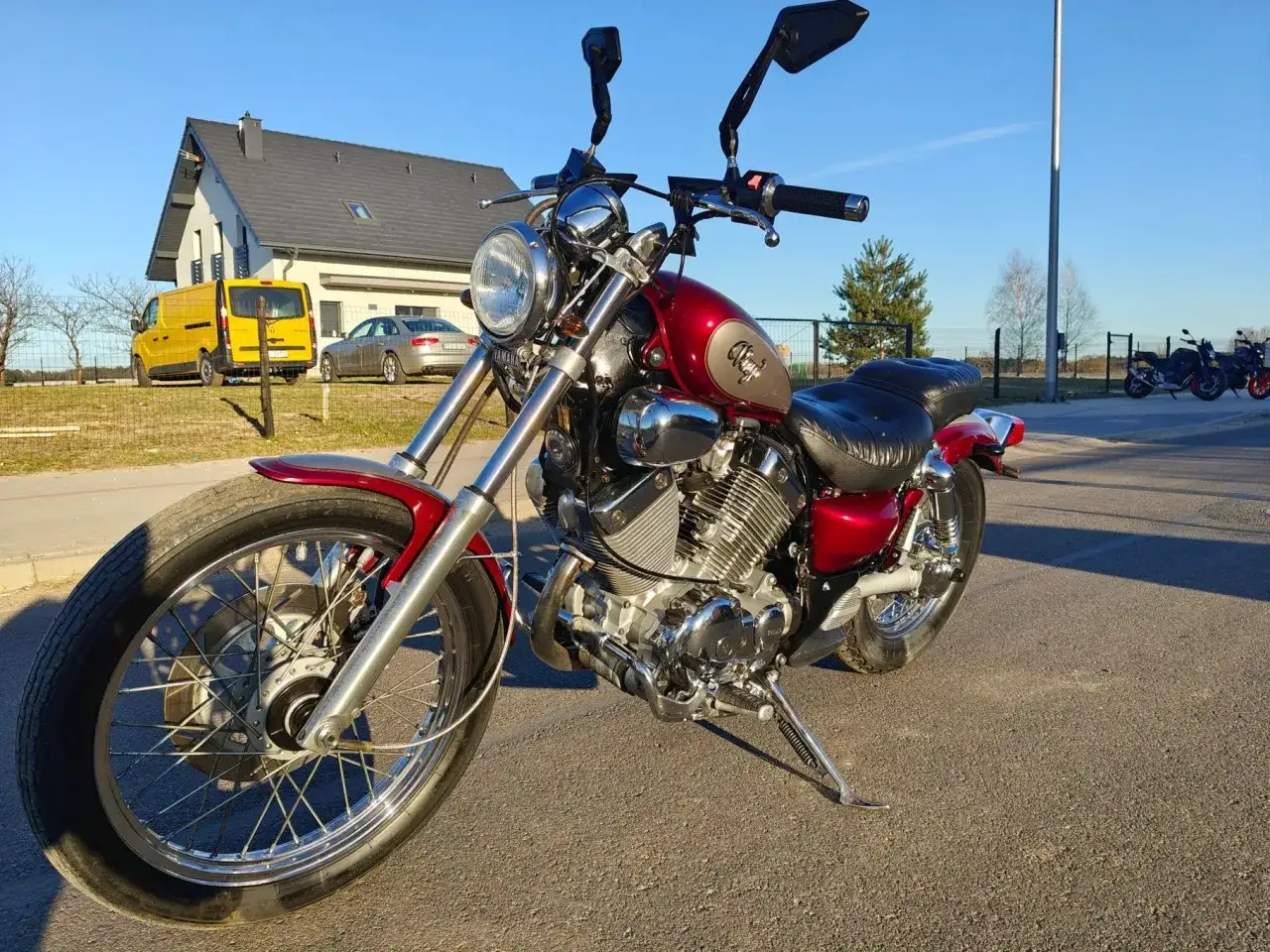 Czerwony motocykl Yamaha Virago 535, z chromowanymi elementami, zaparkowany na zewnątrz. Idealny do poznania jego danych technicznych.
