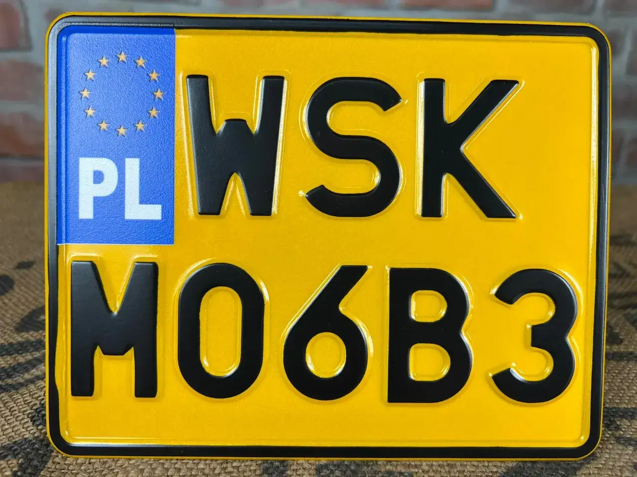 Żółta tablica rejestracyjna z oznaczeniem PL i napisem WSK MO6B3.