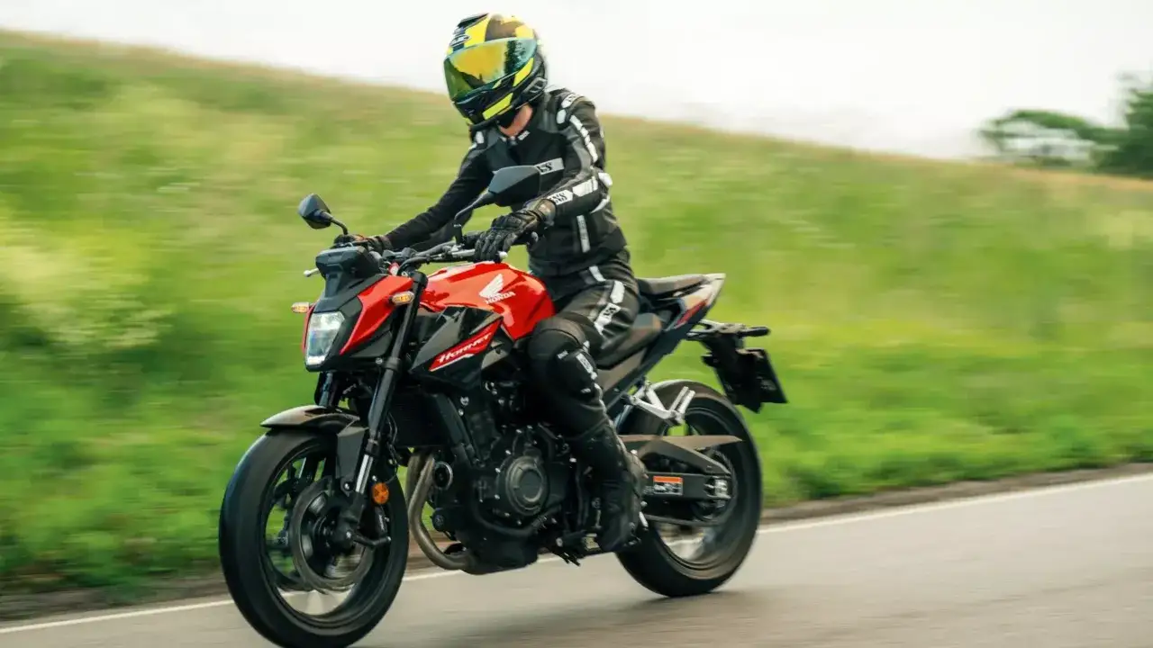 Motocyklista w kombinezonie jedzie czerwonym Hondą Hornet 500. Poznaj honda cb 500 dane techniczne i poczuj wolność na drodze.