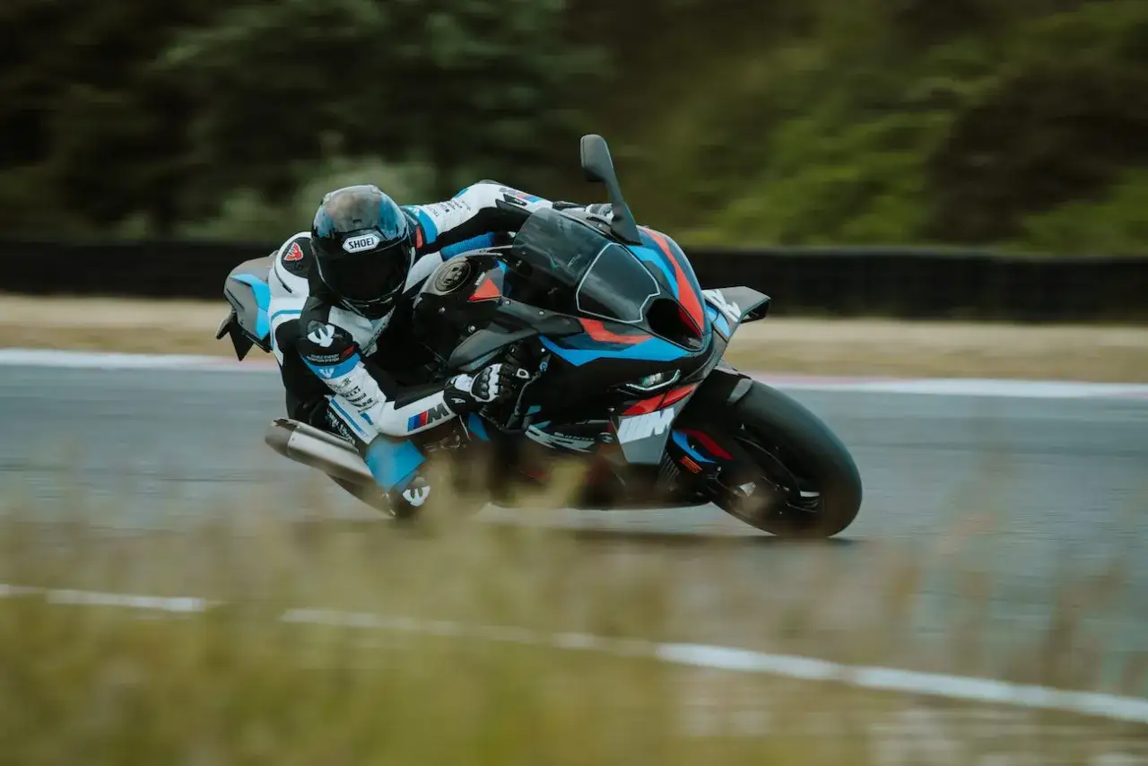 Motocyklista w kombinezonie ściga się na torze na sportowym motocyklu BMW M1000RR.