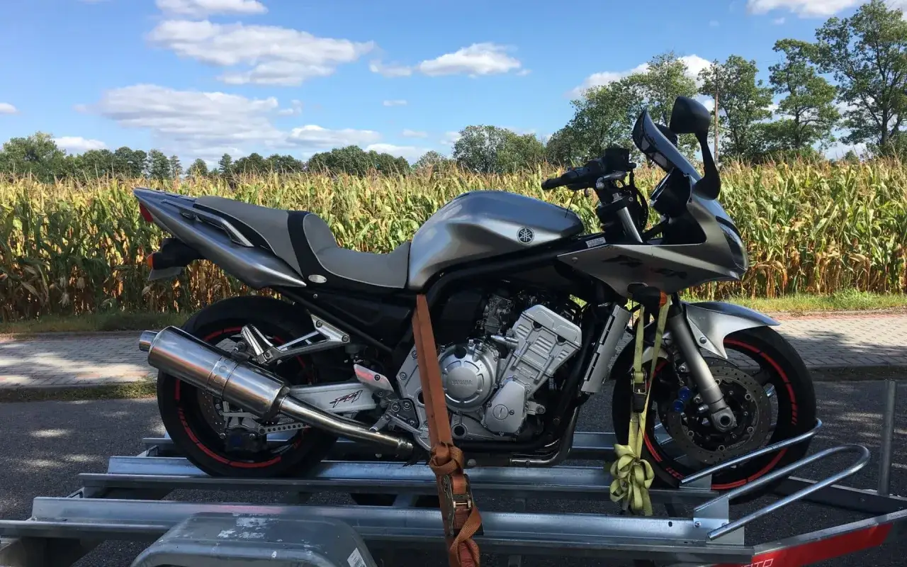 Srebrny motocykl Yamaha Fazer na przyczepce, gotowy do transportu. Idealna okazja na tanie motocykle z Niemiec.