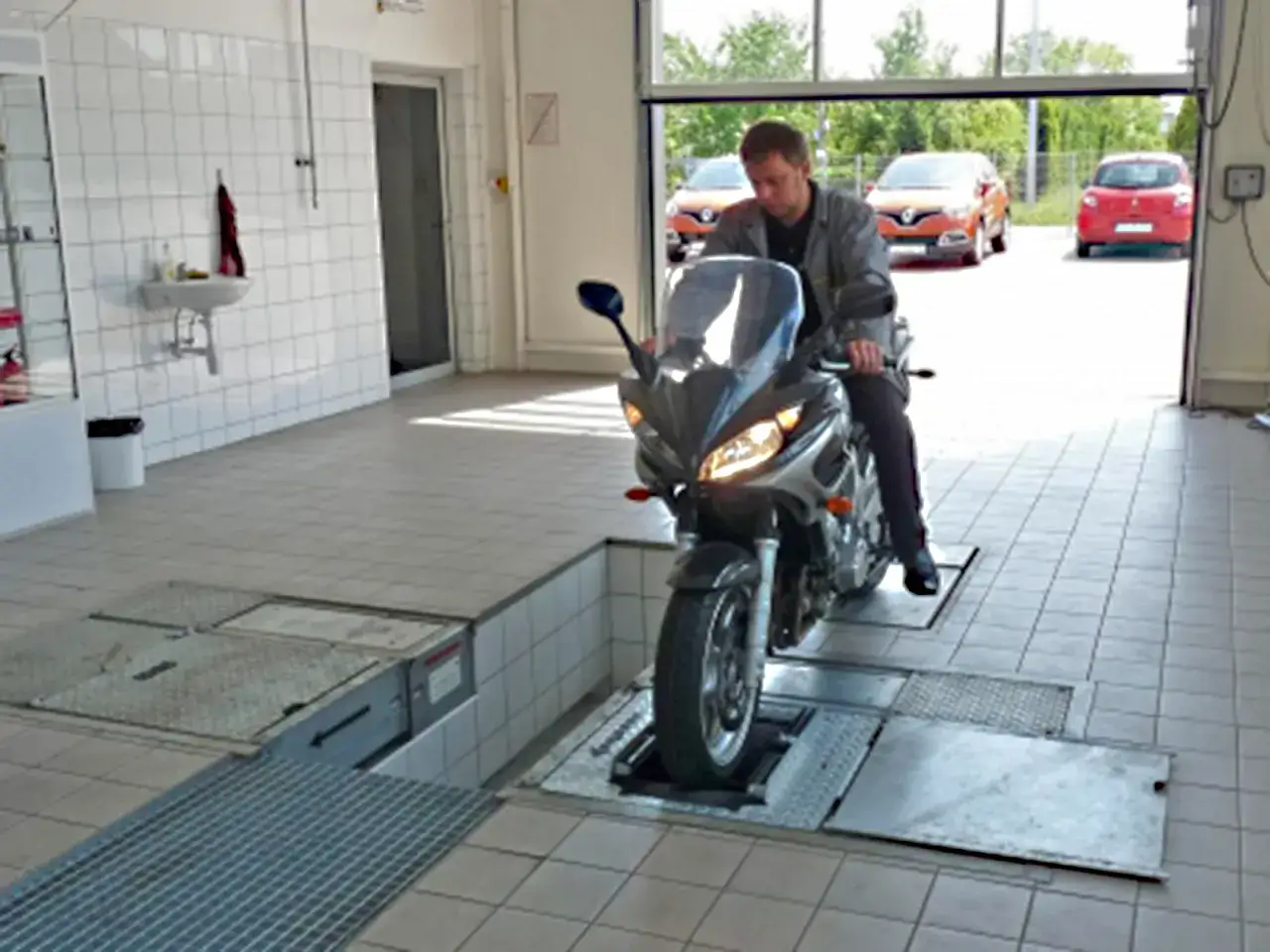 Mechanik na motorowerze na podnośniku. Zastanawiasz się, ile kosztuje przegląd motoroweru?