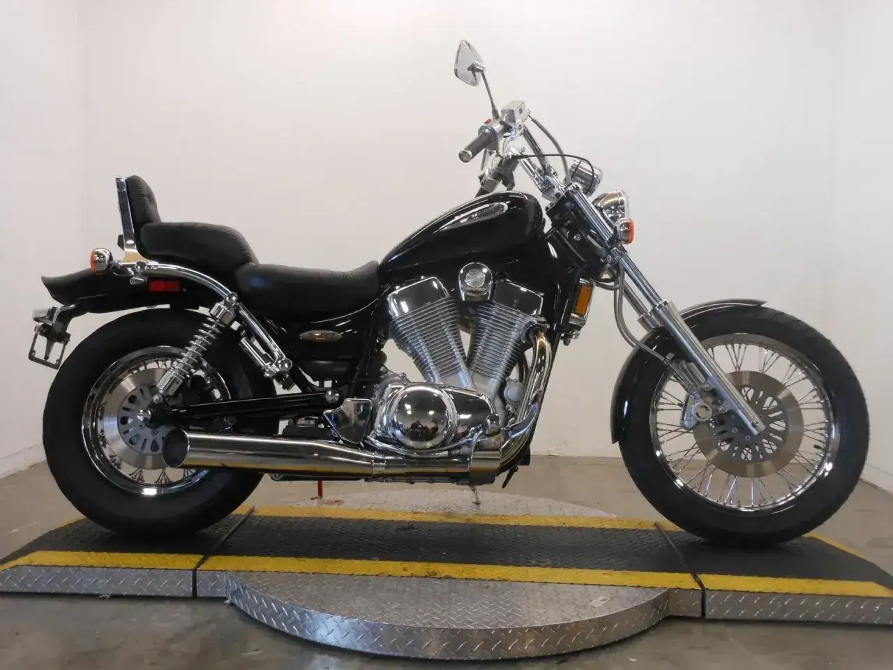 Czarny motocykl Suzuki Intruder z chromowanymi elementami, siedzeniem pasażera i bagażnikiem.