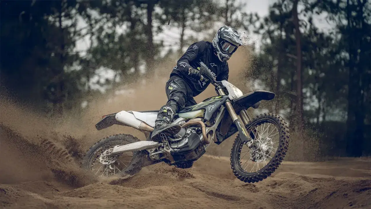 Motocyklista w kasku i stroju enduro szaleje na piaszczystym torze. Czy enduro można jeździć po ulicy? Ten motocykl wygląda na gotowego na wszystko!