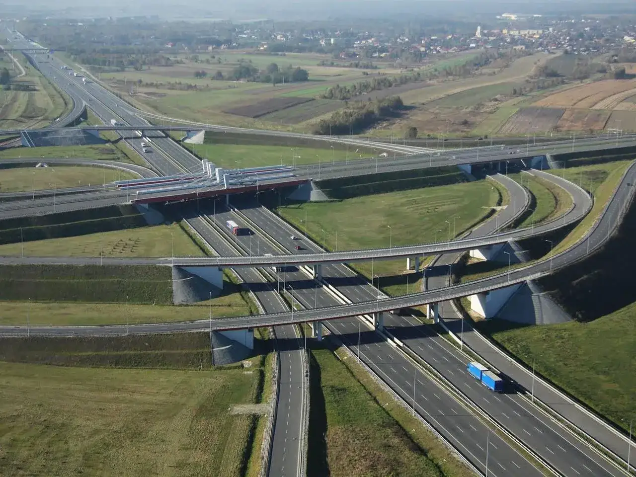 Rozległe skrzyżowanie autostrad, gdzie drogi przecinają się na różnych poziomach, tworząc złożoną sieć. To definicja skrzyżowania w praktyce.