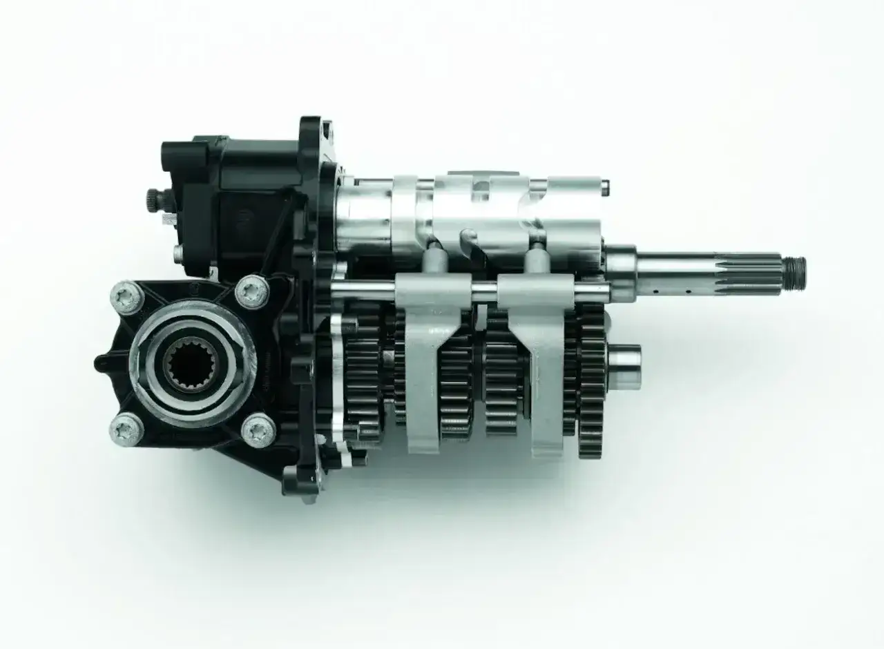 Mechanizm zmiany biegów w motocyklu, z widocznymi zębatkami i wałkami.