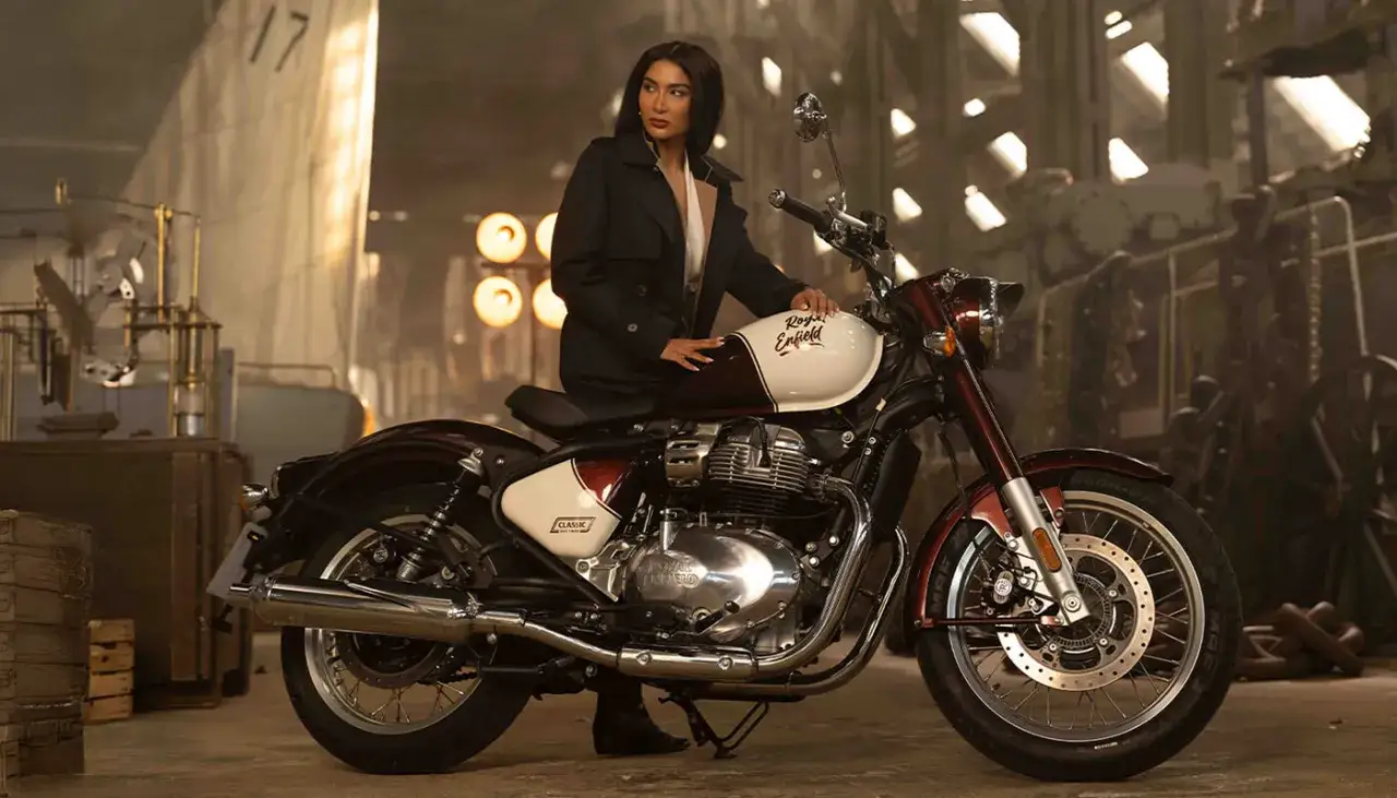 Elegancka kobieta na motocyklu Royal Enfield Classic 650 w industrialnym otoczeniu.