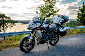 Kawasaki Versys 650 dane techniczne: turystyczny motocykl gotowy na przygodę, z kuframi i bagażem, na tle malowniczego krajobrazu.