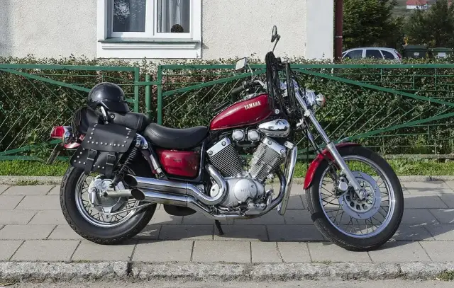 Czerwony motocykl Yamaha Virago 535 z sakwami i kaskiem. Dane techniczne tego klasyka są imponujące.